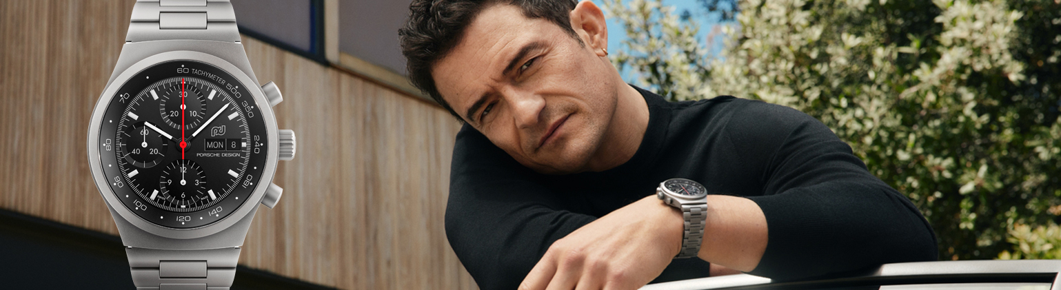 Reloj Porsche Design Chronograph con Orlando Bloom apoyado en un coche