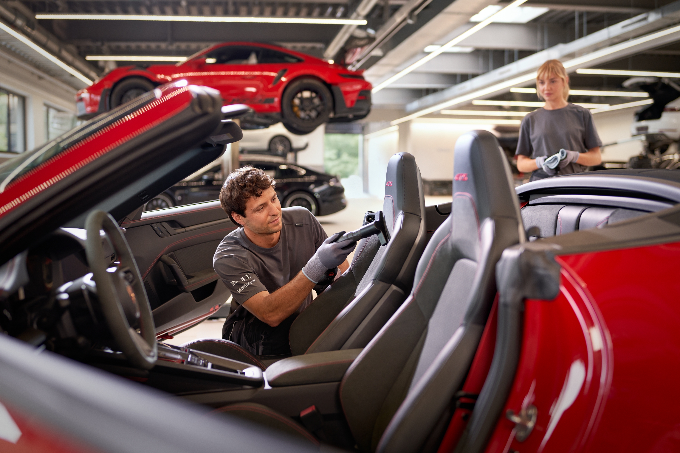 Técnico de Porsche Service limpiando el interior de un Porsche descapotable