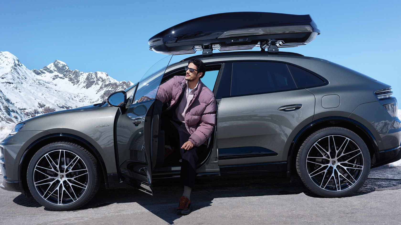 Porsche Macan con cofre de techo Porsche y conductor junto al vehículo